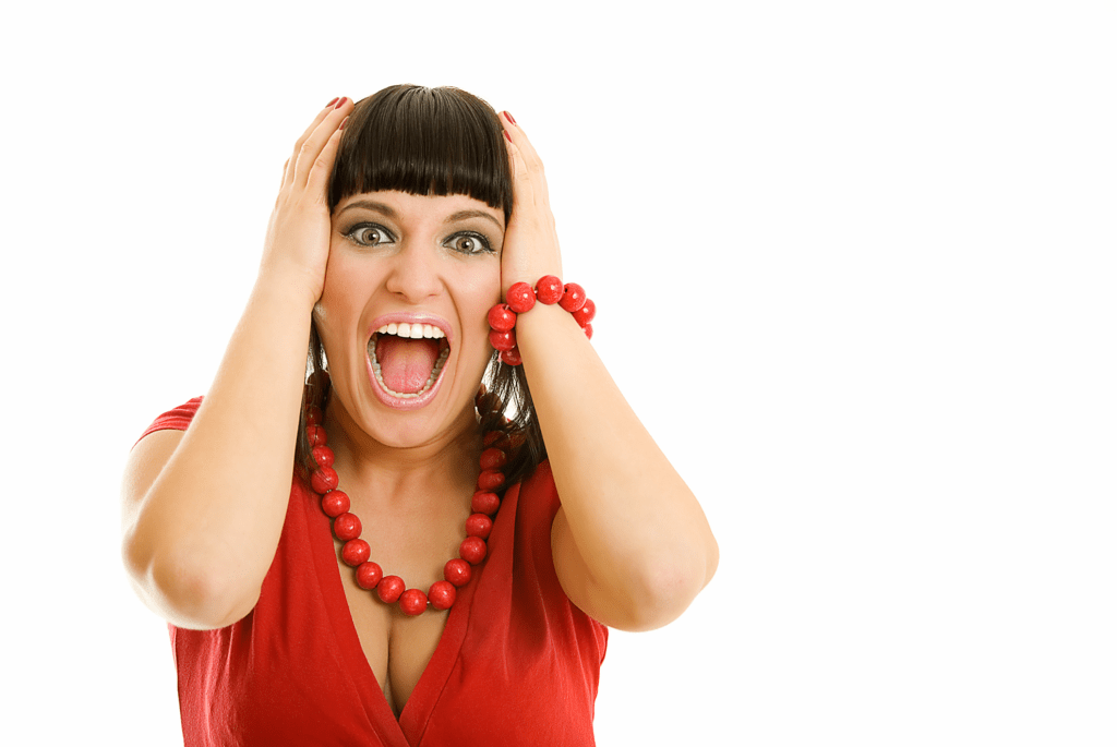 A woman with a shocked expression holds her head in frustration