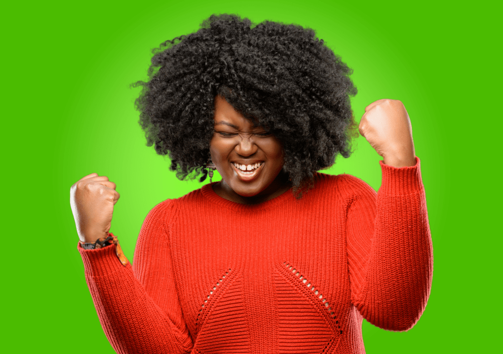 Joyful woman in a red sweater raises her fists in triumph against a bright green background