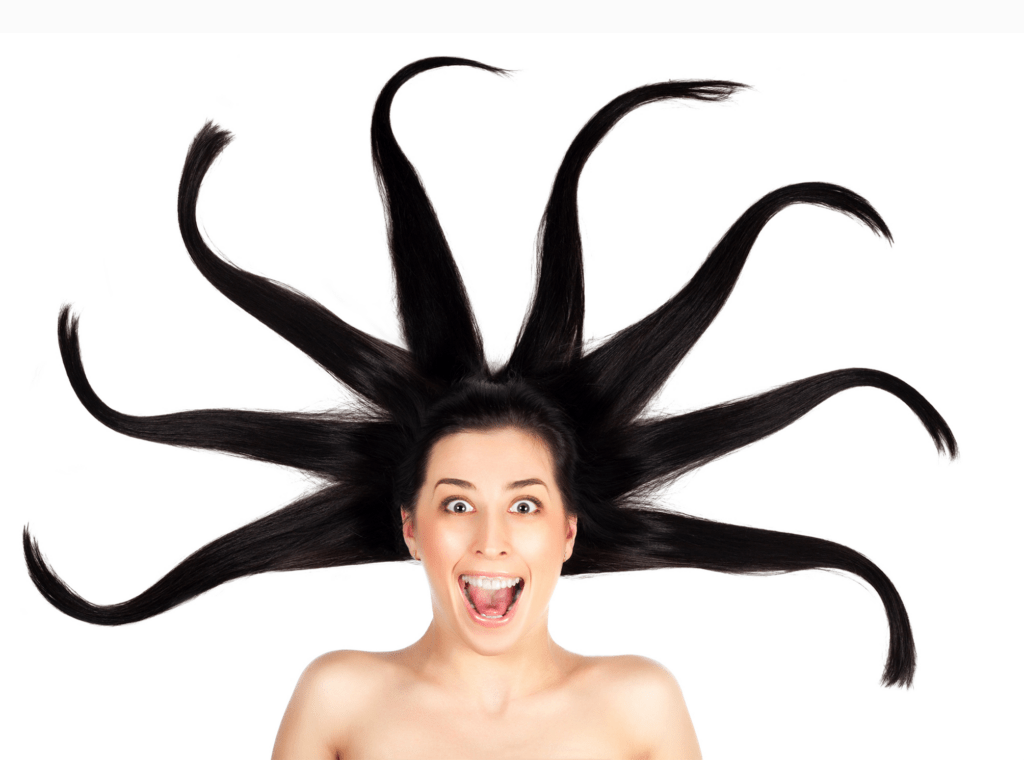 A woman with long, flowing hair styled in an eye-catching burst around her head, playfully covering her mouth. The image highlights creativity in hair design.