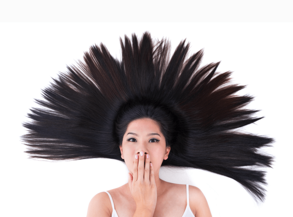 A woman with long, flowing hair styled in an eye-catching burst around her head, playfully covering her mouth. The image highlights creativity in hair design.