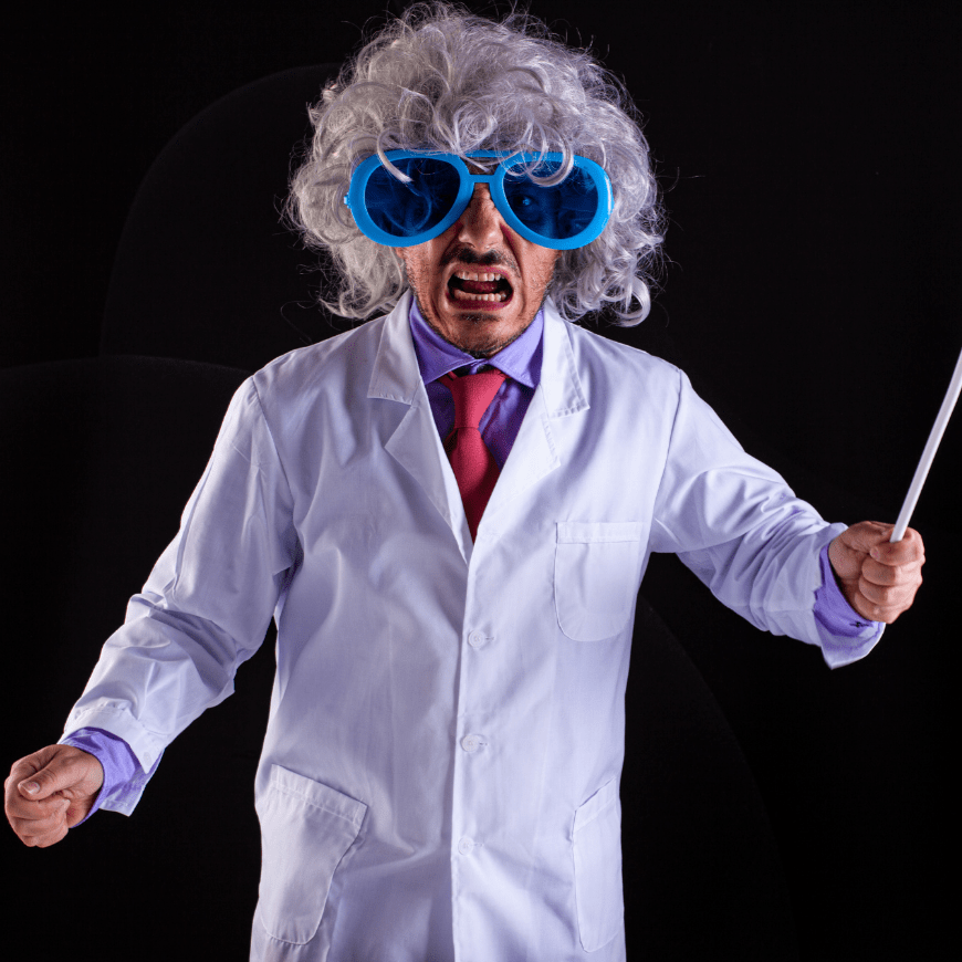 A man dressed as a mad scientist in a white lab coat and oversized blue goggles, with wild gray hair and a comical, exaggerated angry expression.
